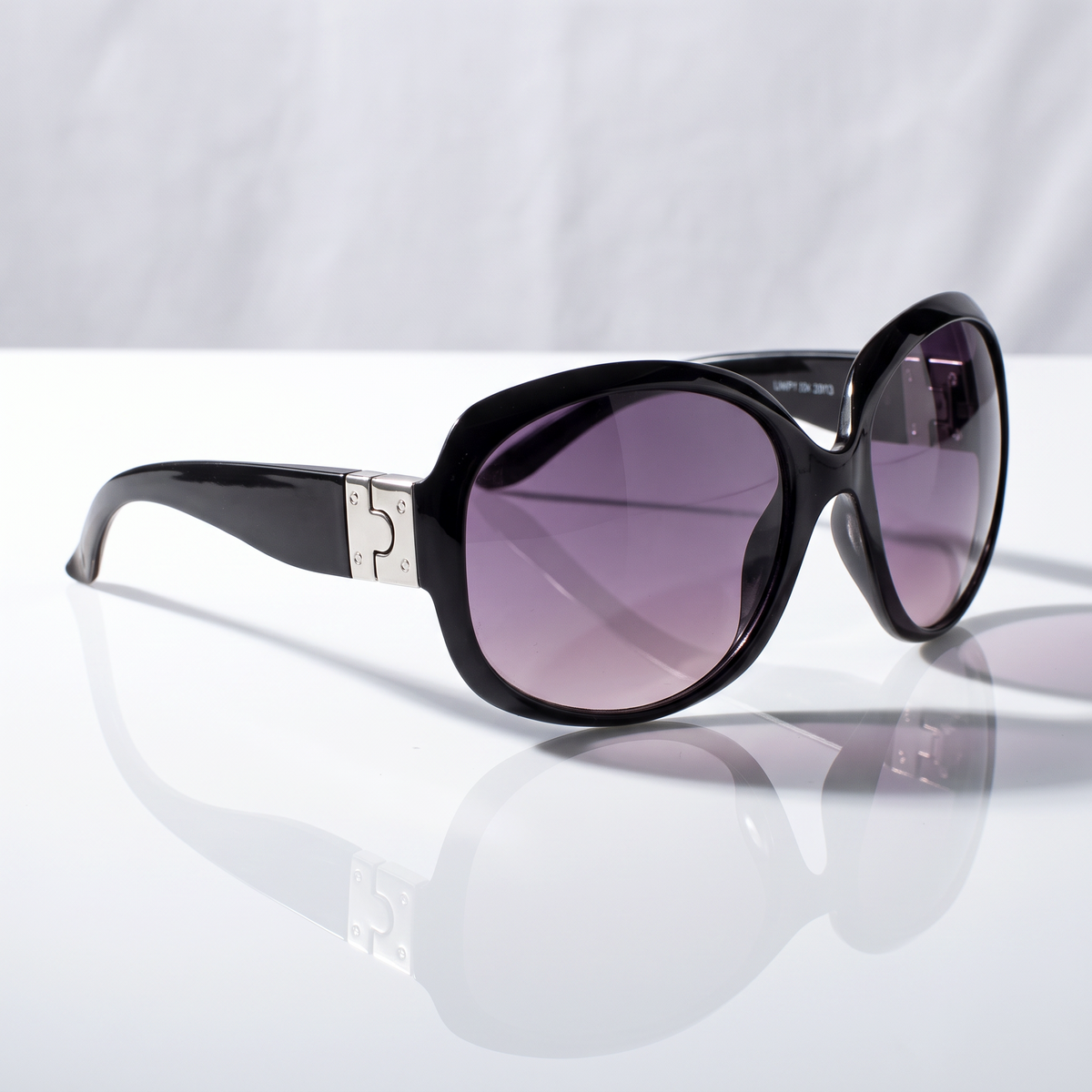 Eyelevel-UK Lucy oversized geometric sunglasses in black and silver with grey gradient lenses on a reflective surface