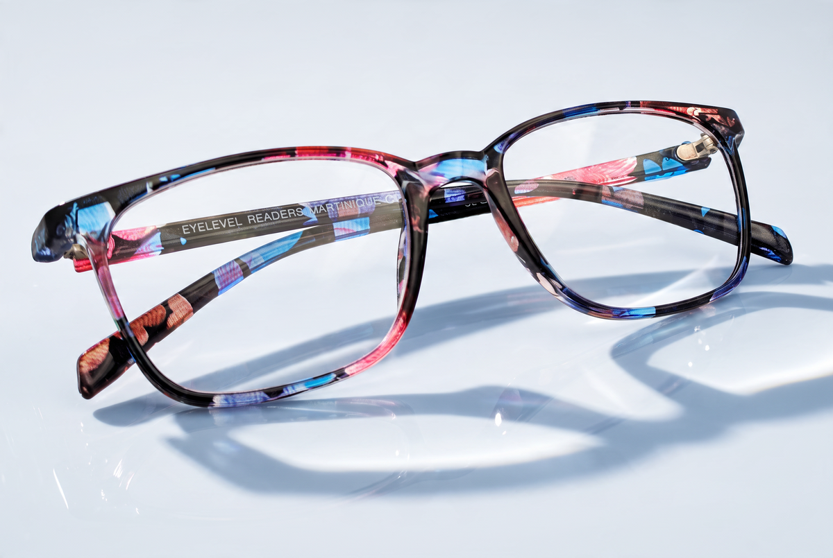 Eyelevel-UK Martinique reading glasses with a multicolour floral square plastic frame on a reflective surface.