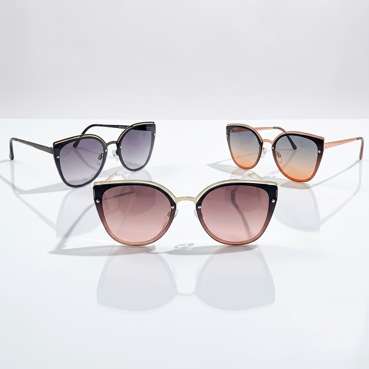 Eyelevel-UK Rosie cat-eye sunglasses in black, rose gold, and light gold with gradient lenses on a white surface.