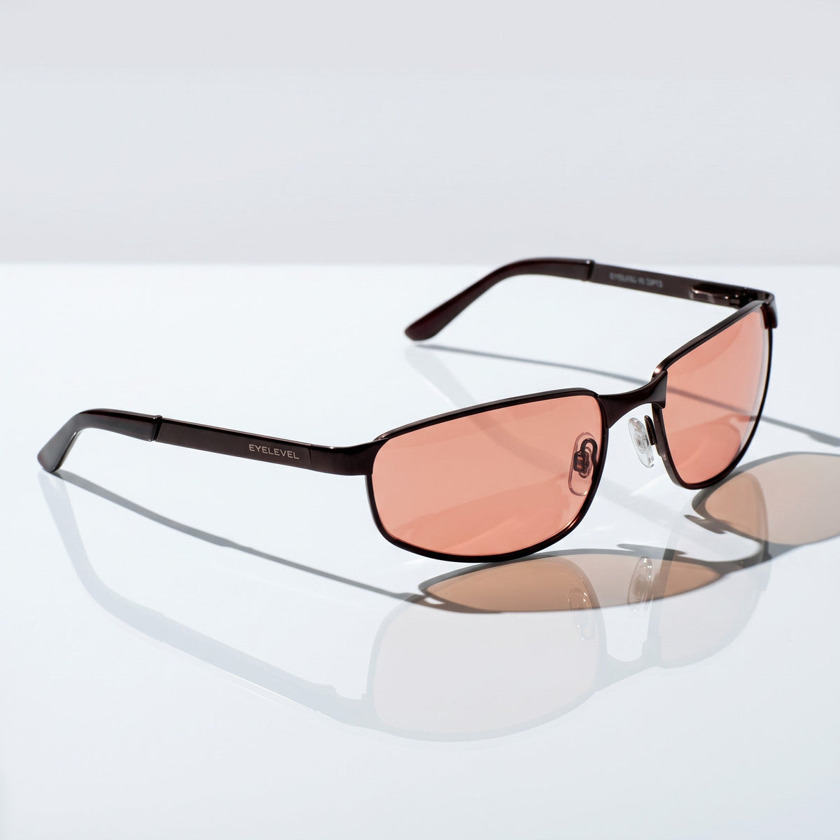 Eyelevel-UK Stirling polarized driving sunglasses with gunmetal frame and copper lenses on a reflective surface.