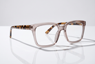 Eyelevel-UK Cayman reading glasses with a pale-pink squared frame and tortoiseshell temples on a reflective surface.