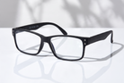 Eyelevel-UK Duke reading glasses with a black rectangular plastic frame and clear magnifying lenses on a white surface.