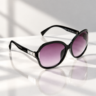 Eyelevel-UK Hayley oversized black sunglasses with silver stone detail and grey gradient lenses on a reflective surface