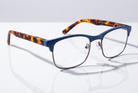 Eyelevel-UK Henley reading glasses with a blue and tortoiseshell rectangular frame on a reflective white surface.