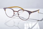 Eyelevel-UK Honduras reading glasses with a two-tone oval frame in brown and mustard yellow on a reflective surface.