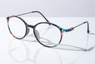 Eyelevel-UK Idaho reading glasses with a round, patterned frame and slim metal temples on a white reflective surface.