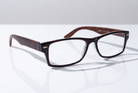 Eyelevel-UK Kennedy reading glasses with a black and wood effect rectangular frame on a reflective white surface.