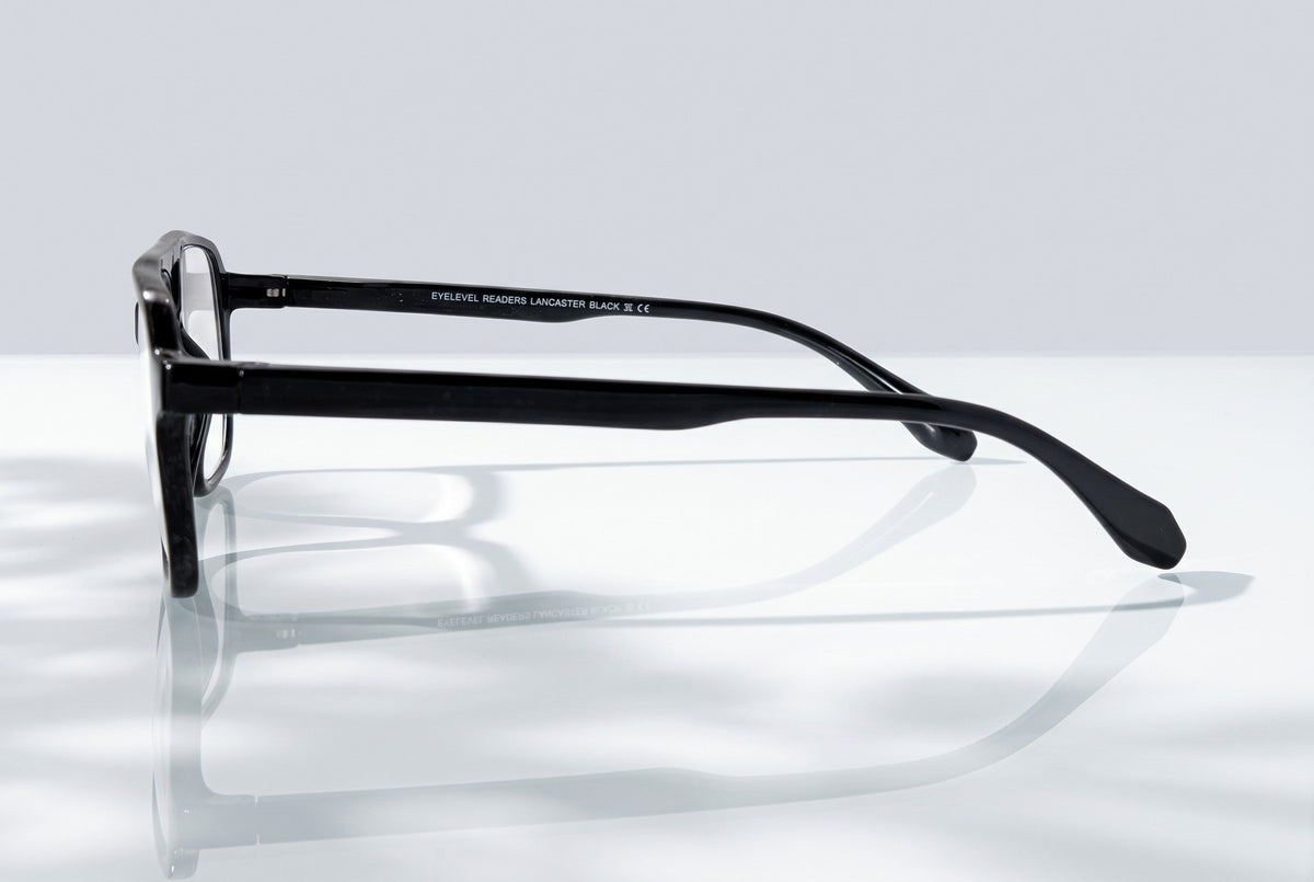 Eyelevel-UK Lancaster black square reading glasses shown from a side profile view on a reflective surface.