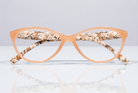 Eyelevel-UK Mexico reading glasses with a beige cat-eye frame and animal print inner temples on a reflective surface.