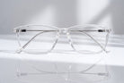Eyelevel-UK Oregon reading glasses with a transparent softly squared plastic frame on a reflective surface.