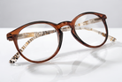 Eyelevel-UK Royal reading glasses with a brown round frame and animal print temple details on a reflective surface.