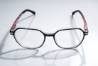 Eyelevel-UK St Kitts reading glasses with translucent grey squared frames and patterned black and red temples.