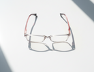 Eyelevel-UK St Kitts reading glasses with translucent grey squared frames and patterned temples on a white surface