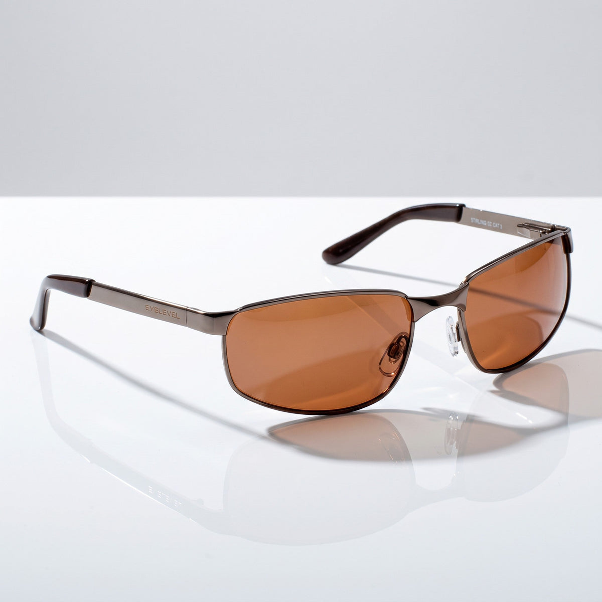 Eyelevel-UK Stirling polarized driving sunglasses with gunmetal frames and copper lenses on a reflective surface.