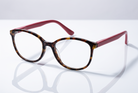 Eyelevel-UK Zurich reading glasses with a tortoiseshell square frame and berry-pink temples on a reflective surface.